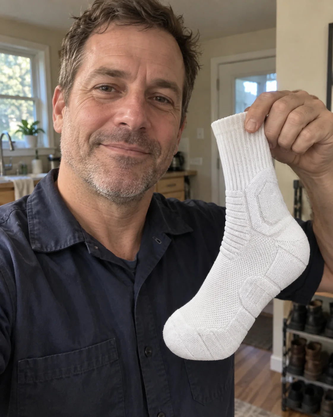 Illustrative casual phone selfie of a man in work clothes holding the white crew sock